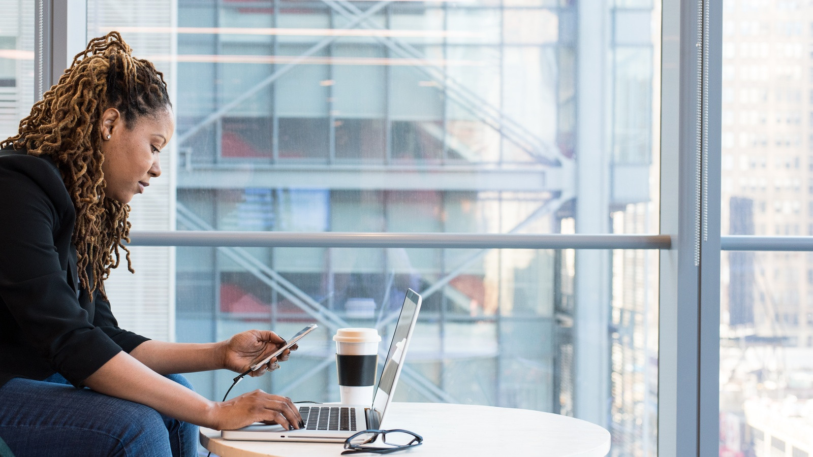 A professional working on a laptop near a large window in a modern tech office